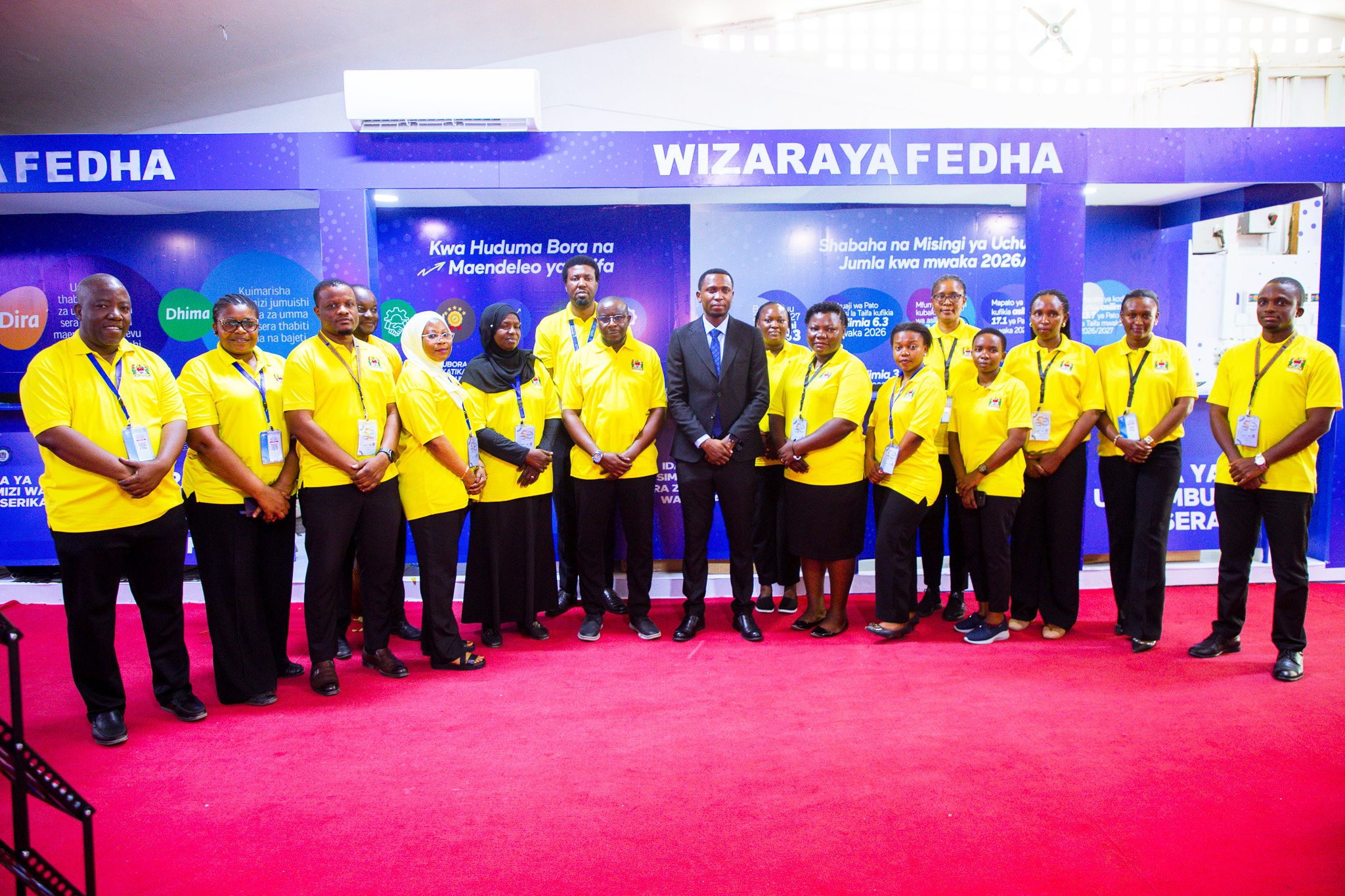 Naibu Waziri wa Fedha, Mhe. Laurent Luswetula (Mb)(katikati), akiwa katika picha ya pamoja na baadhi ya watumishi wa Wizara ya Fedha wanaoshiriki katika Maonesho ya 50 ya Biashara ya Kimataifa ya Dar es Salaam (Sabasaba), yanayoendelea katika Viwanja vya Mwl. J.K Nyerere, jijini Dar es Salaam, wakati alipotembelea banda la wizara hiyo.